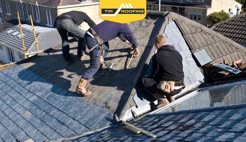 Roofing professionals repairing curling roof shingles on a house.